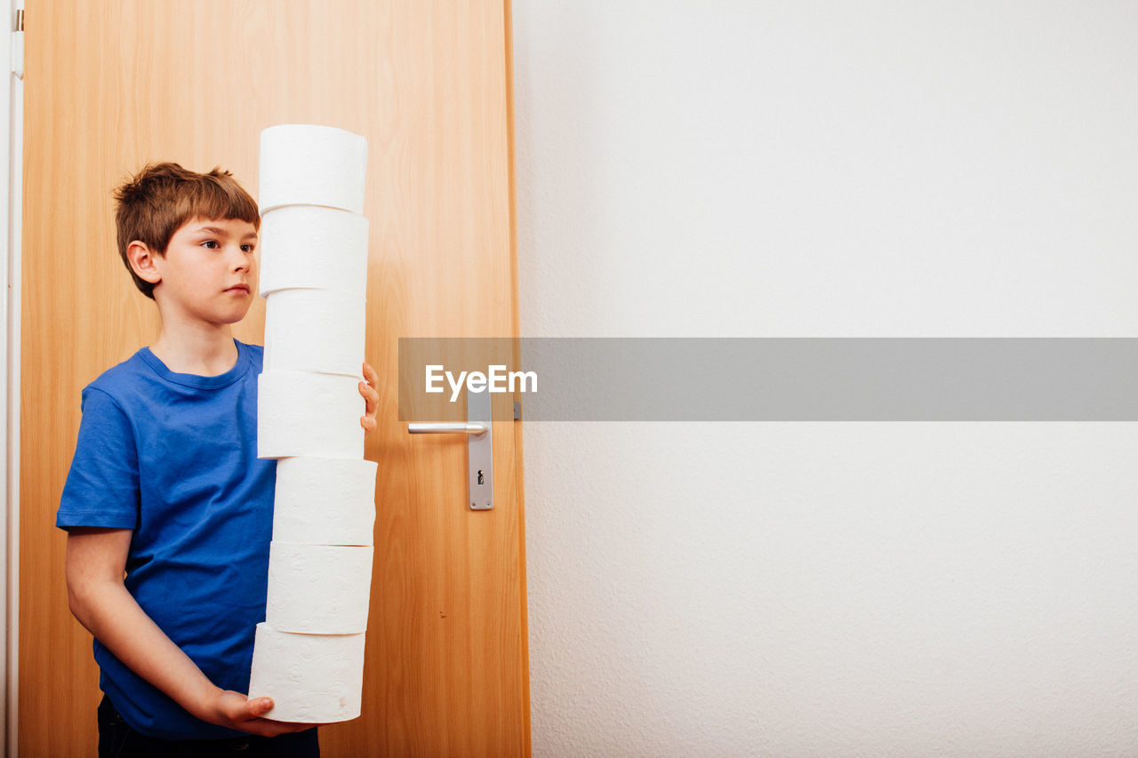 Boy with tissue roles standing by door