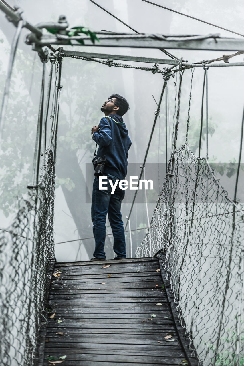 Full length of man standing on bridge during foggy weather