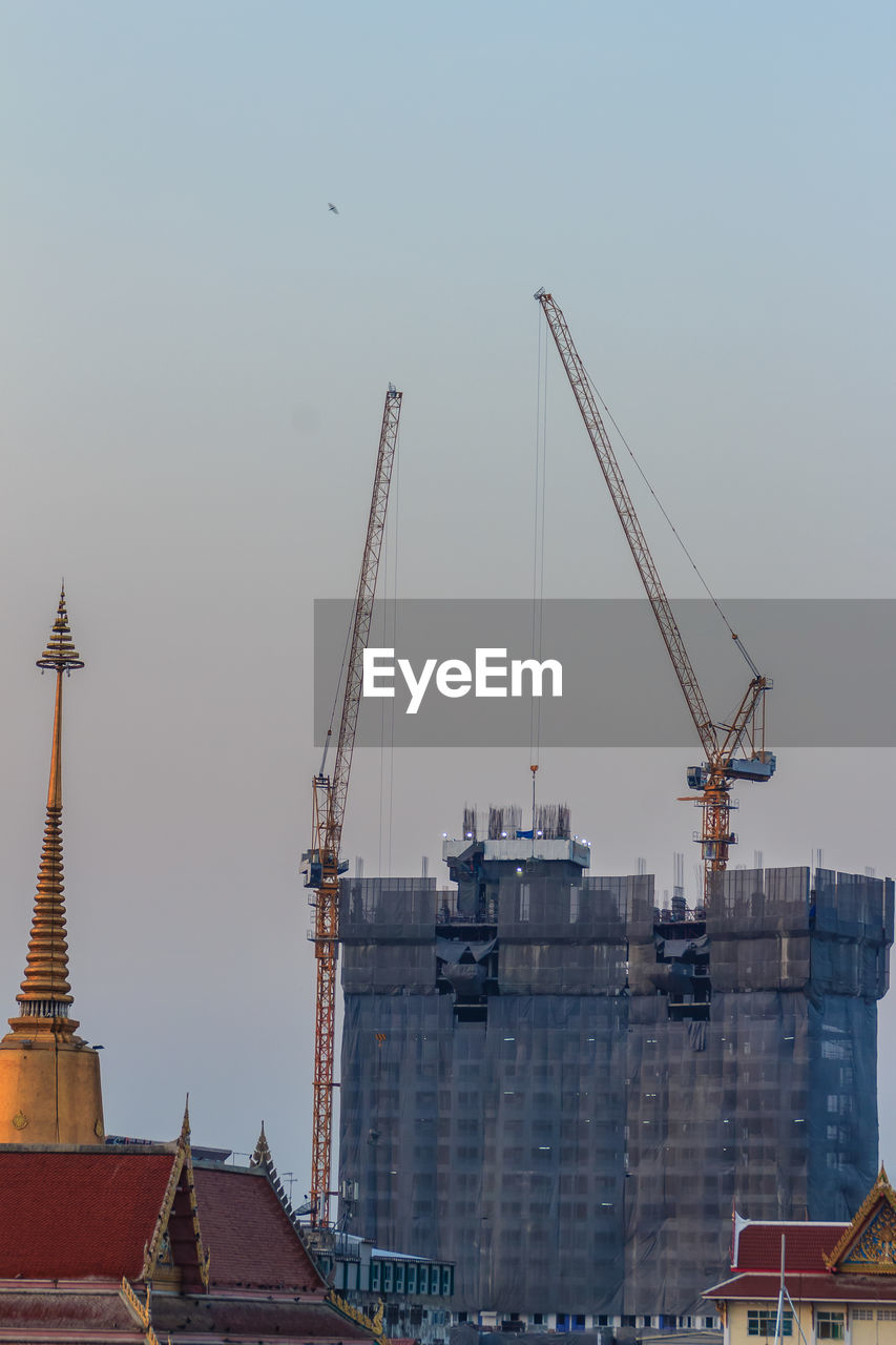 LOW ANGLE VIEW OF CRANES AT CONSTRUCTION SITE AGAINST CLEAR SKY