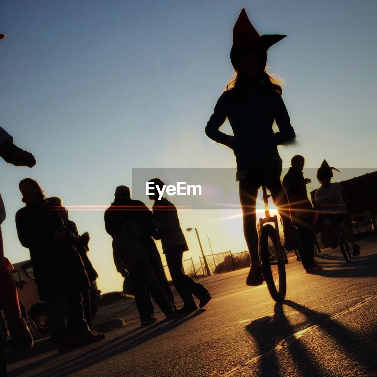 Low angle view of girl riding bicycle against sky during sunset