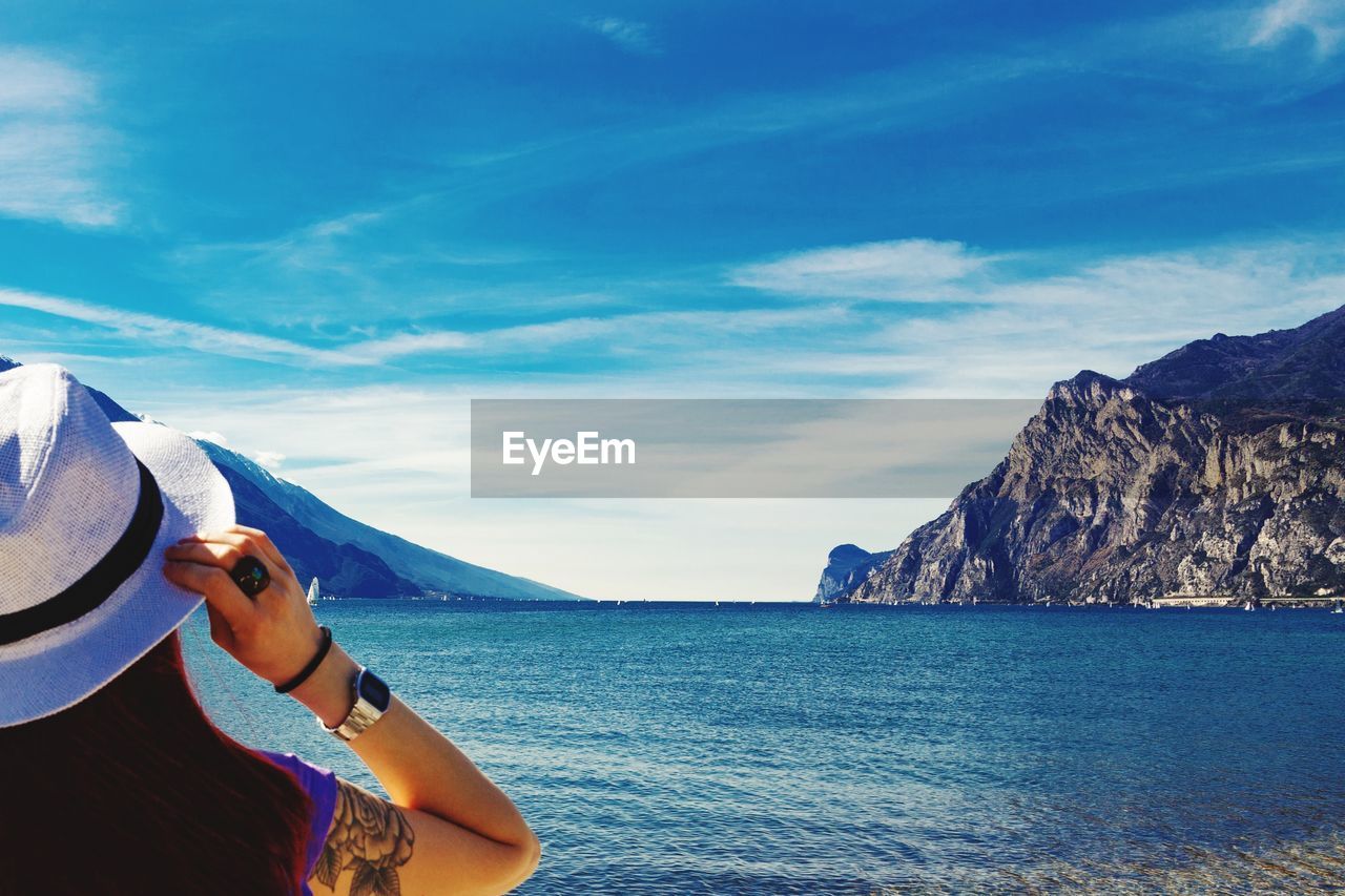 Woman in sea by mountains against sky