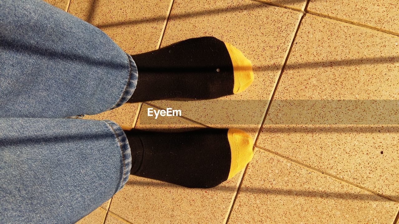 LOW SECTION OF WOMAN ON TILED FLOOR