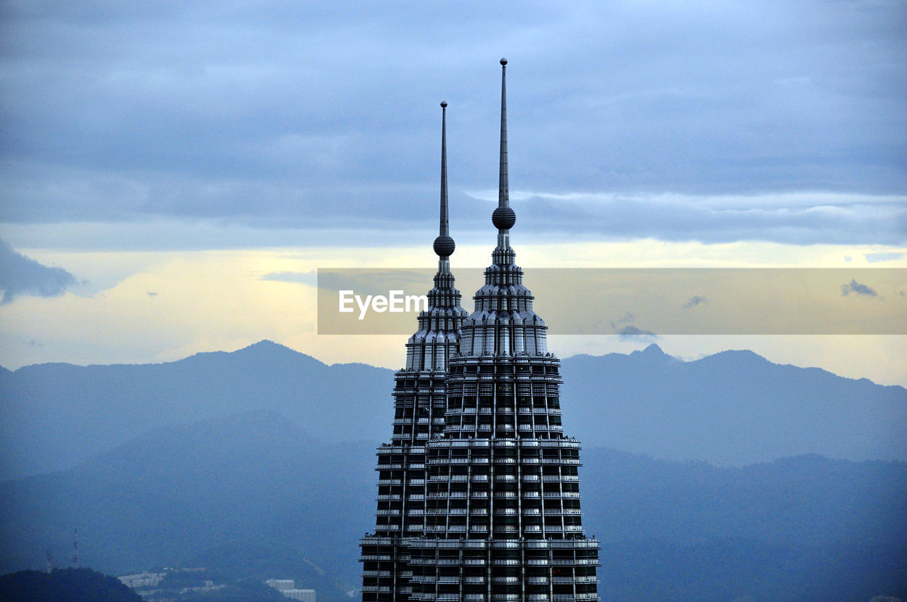 Communications tower in city against sky