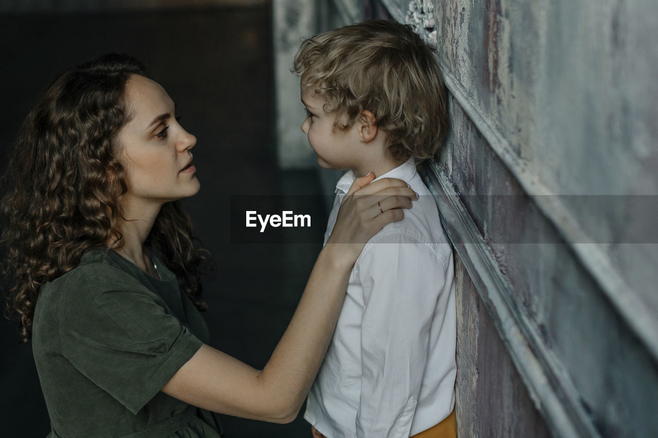 Mother looking at son leaning on wall