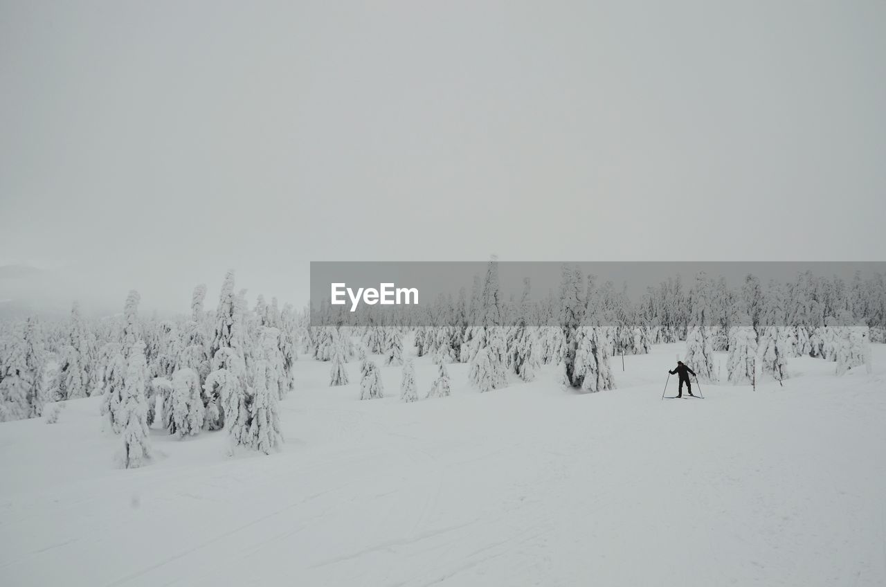 Person skiing on snow covered field against sky