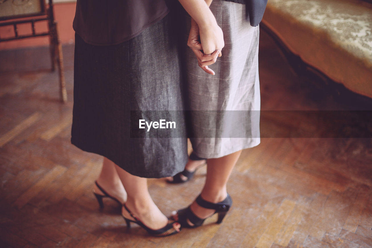 Low section of lesbian couple standing on wooden floor