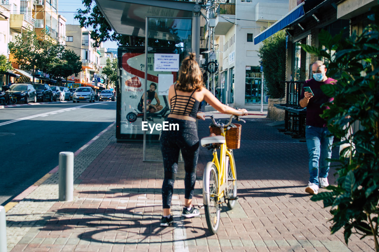 WOMAN RIDING BICYCLE ON SIDEWALK IN CITY