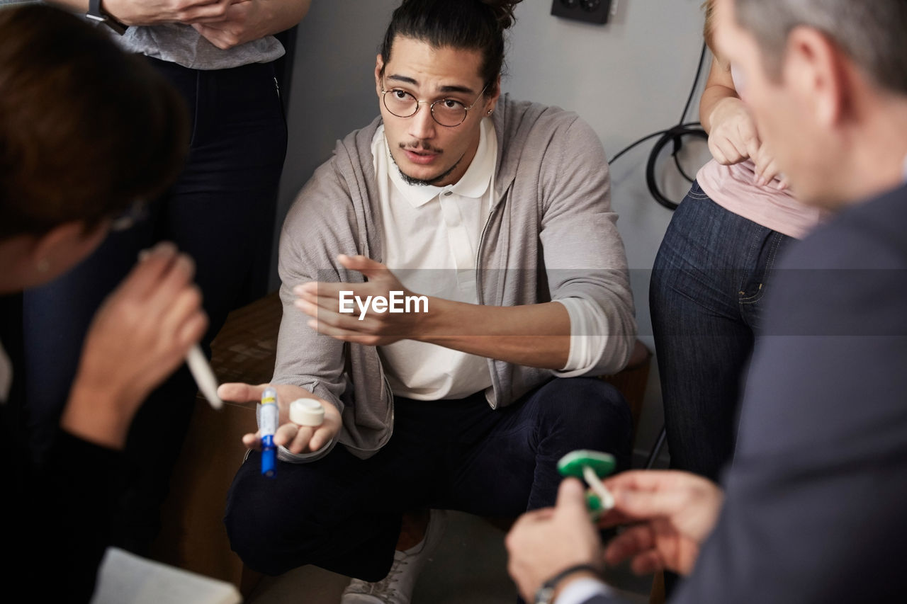 Male entrepreneur explaining project to bank managers during meeting in creative office