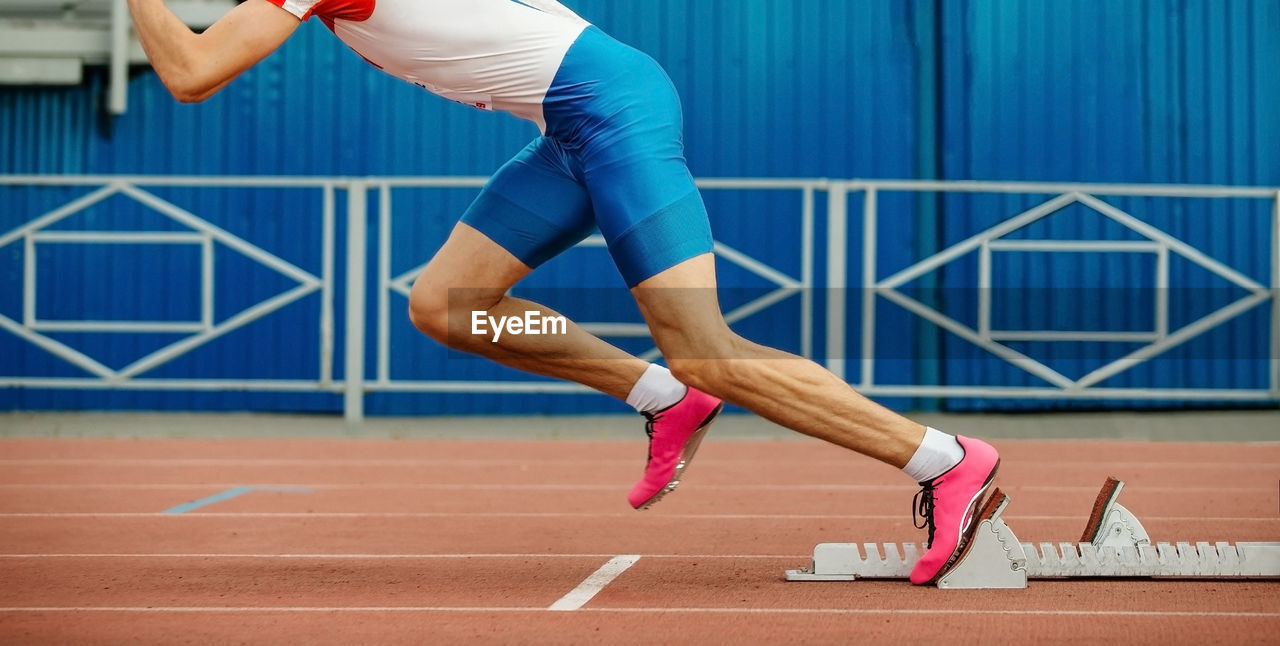 Low section of man running on track