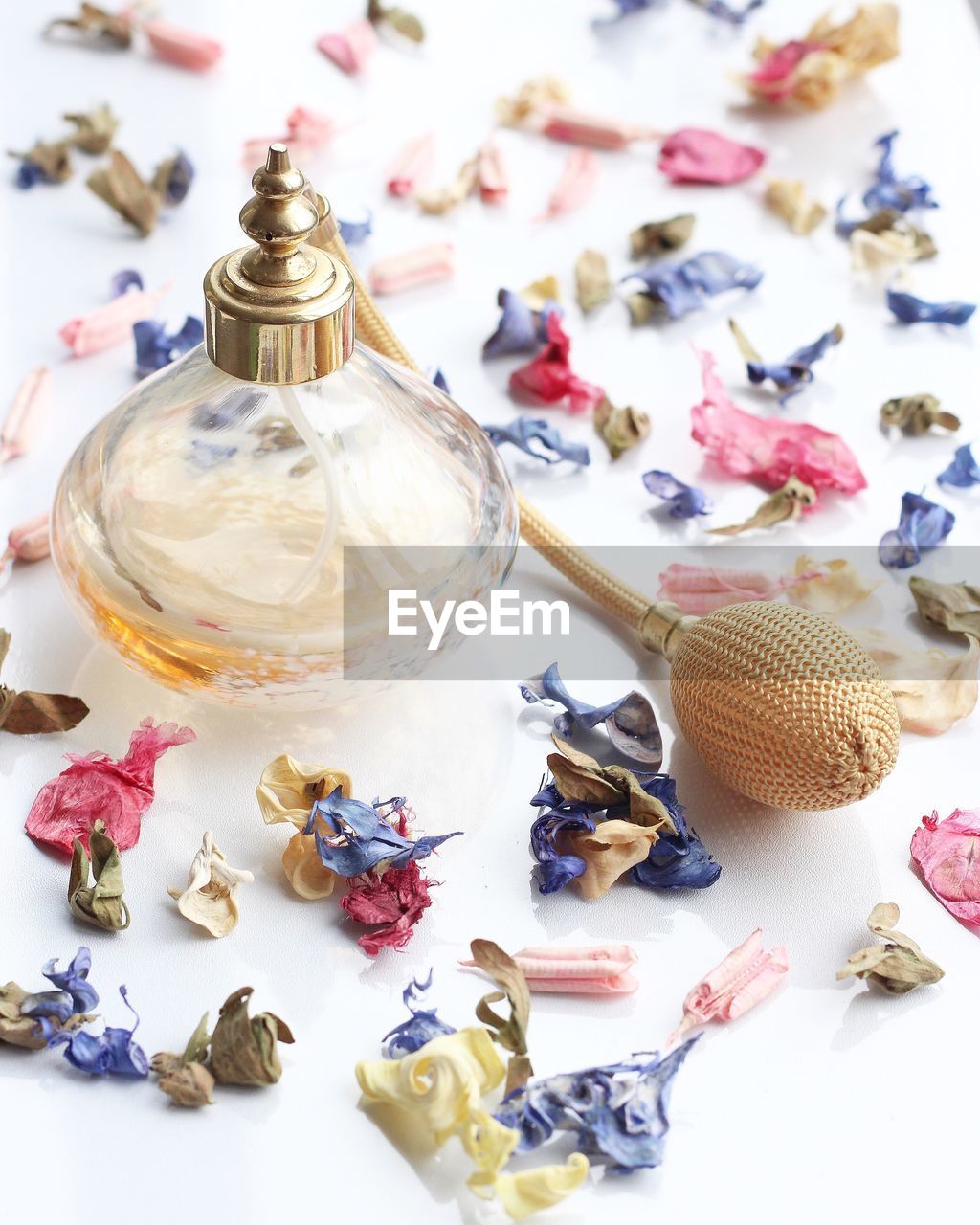 Close-up of perfume bottle and petals on table