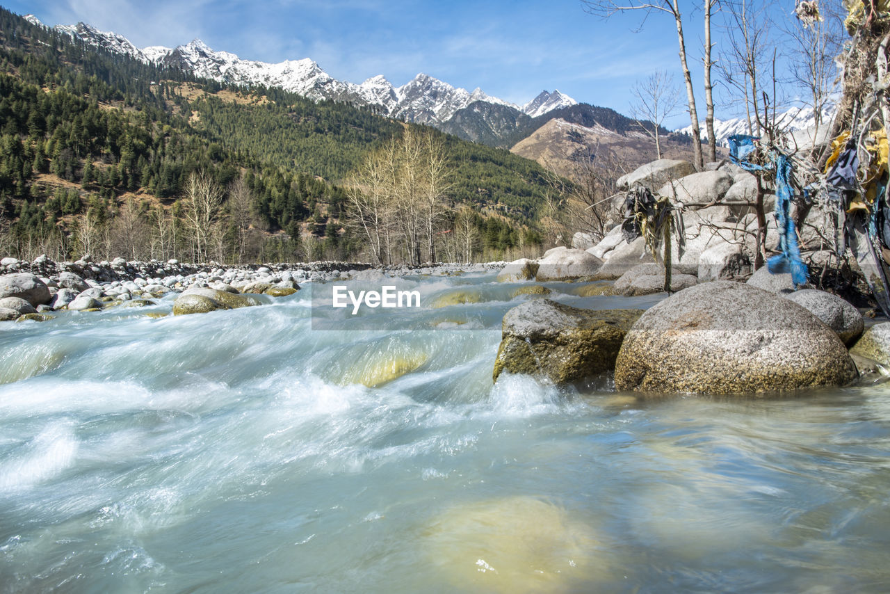 ROCKS IN RIVER AGAINST MOUNTAINS