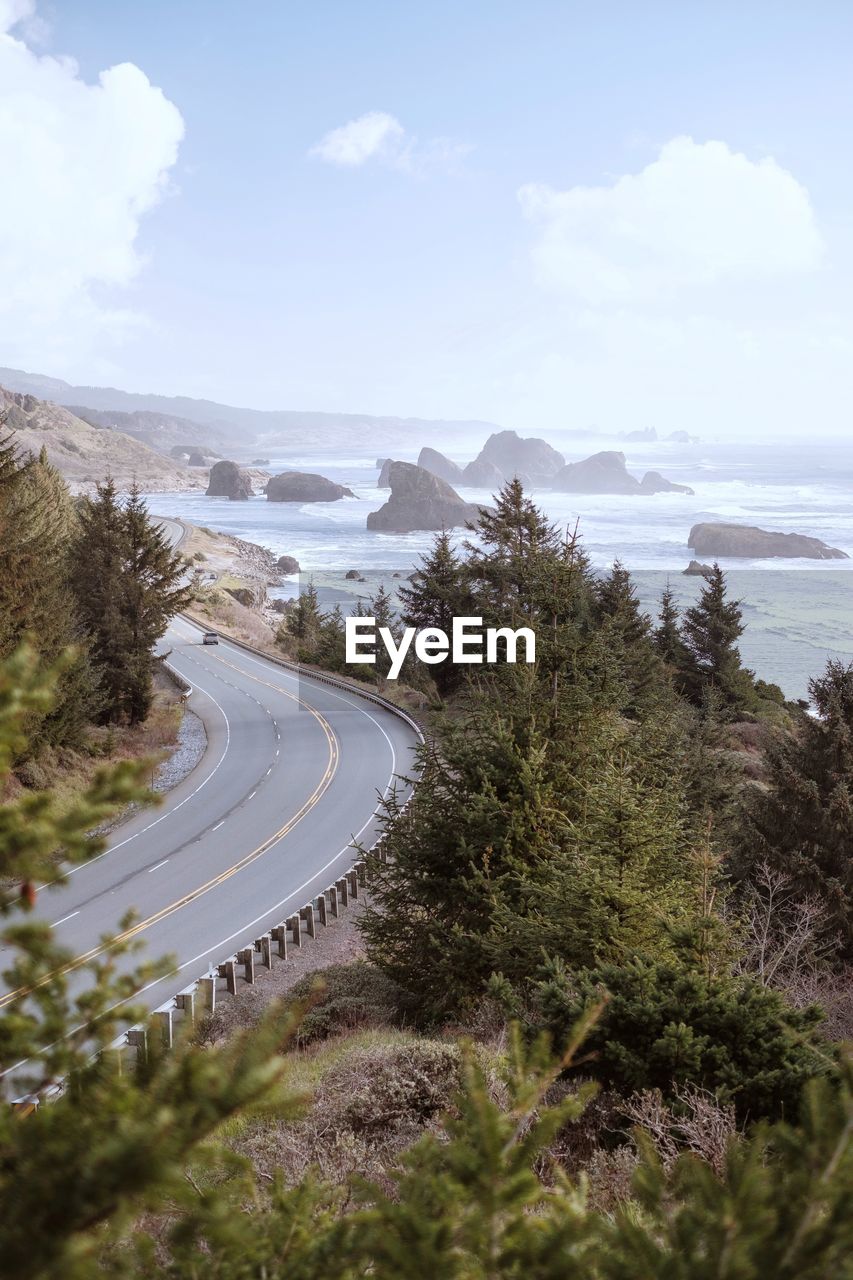 High angle view of coastal road amidst trees against sky