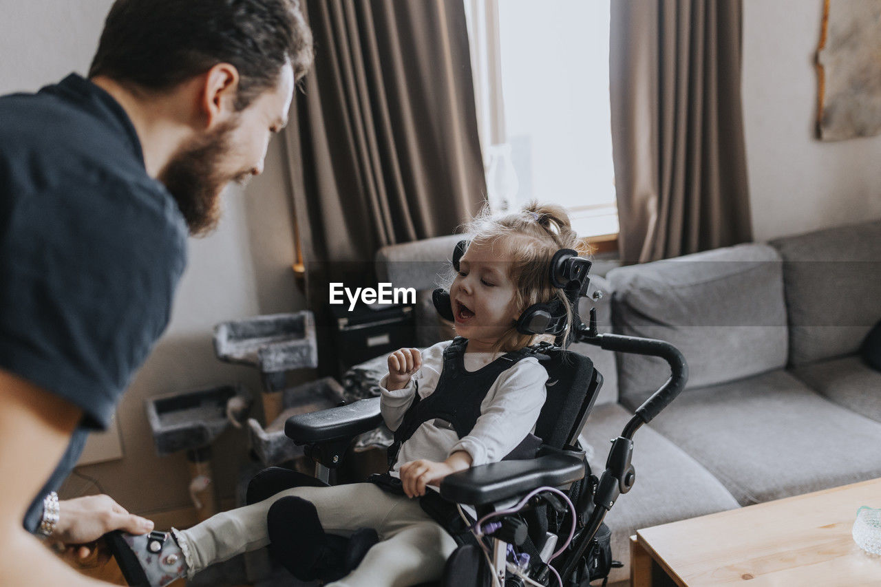 Father taking care of smiling disabled child in wheelchair