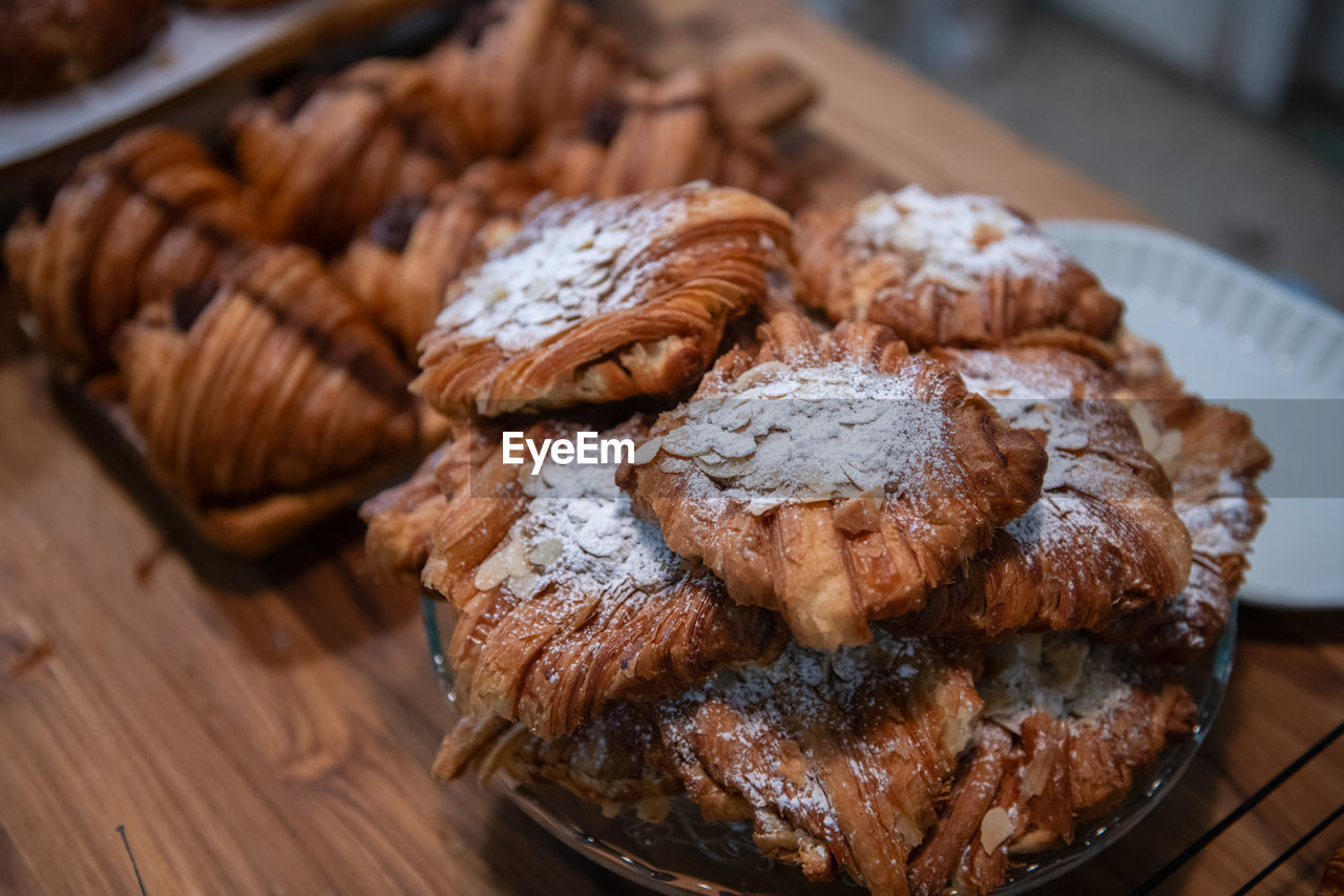 Homemade croissant with sliced almond on glass and on wood background at cafe, bakery concept