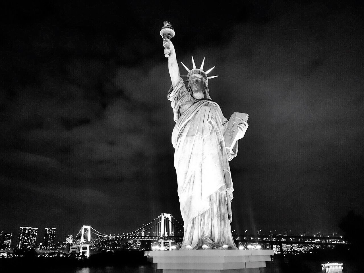 Illuminated statue of liberty by bridge against sky at night