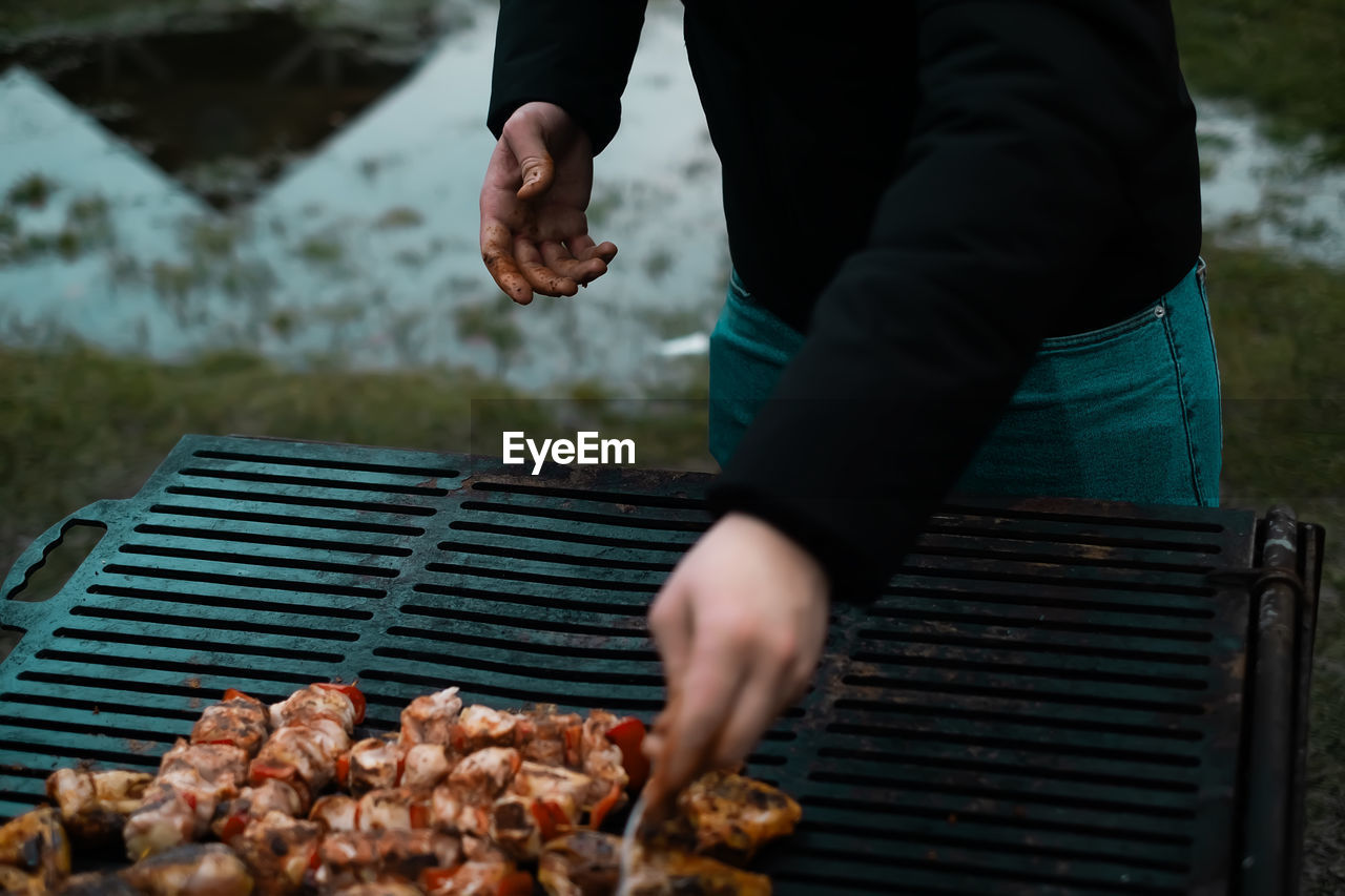 Man frying meat skewers on the grill, home food concept