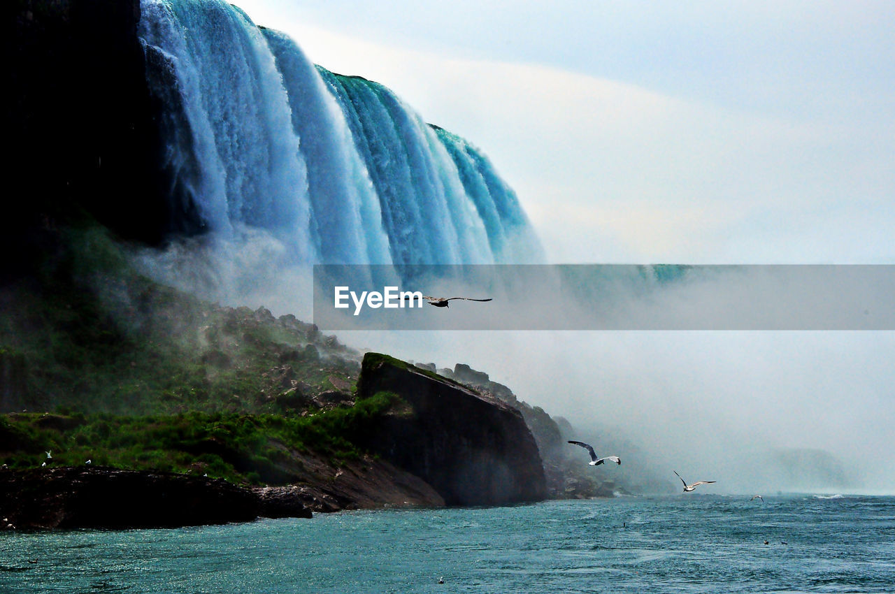 Scenic view of waterfall sea against sky