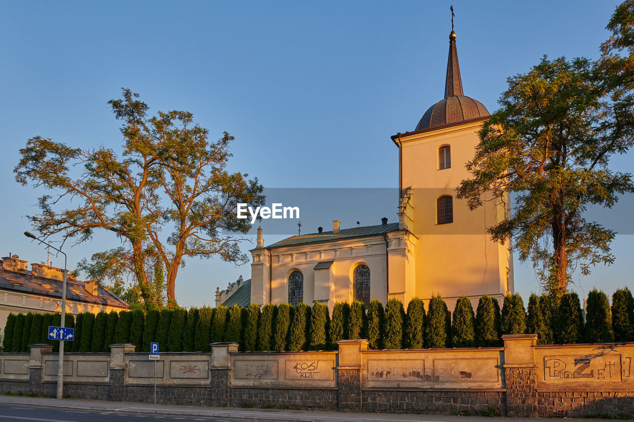 architecture, built structure, building exterior, tree, sky, building, plant, travel destinations, religion, nature, place of worship, city, history, travel, the past, belief, blue, tower, landmark, tourism, clear sky, town, spirituality, street, no people, outdoors, château, sunny, estate, landscape, business finance and industry