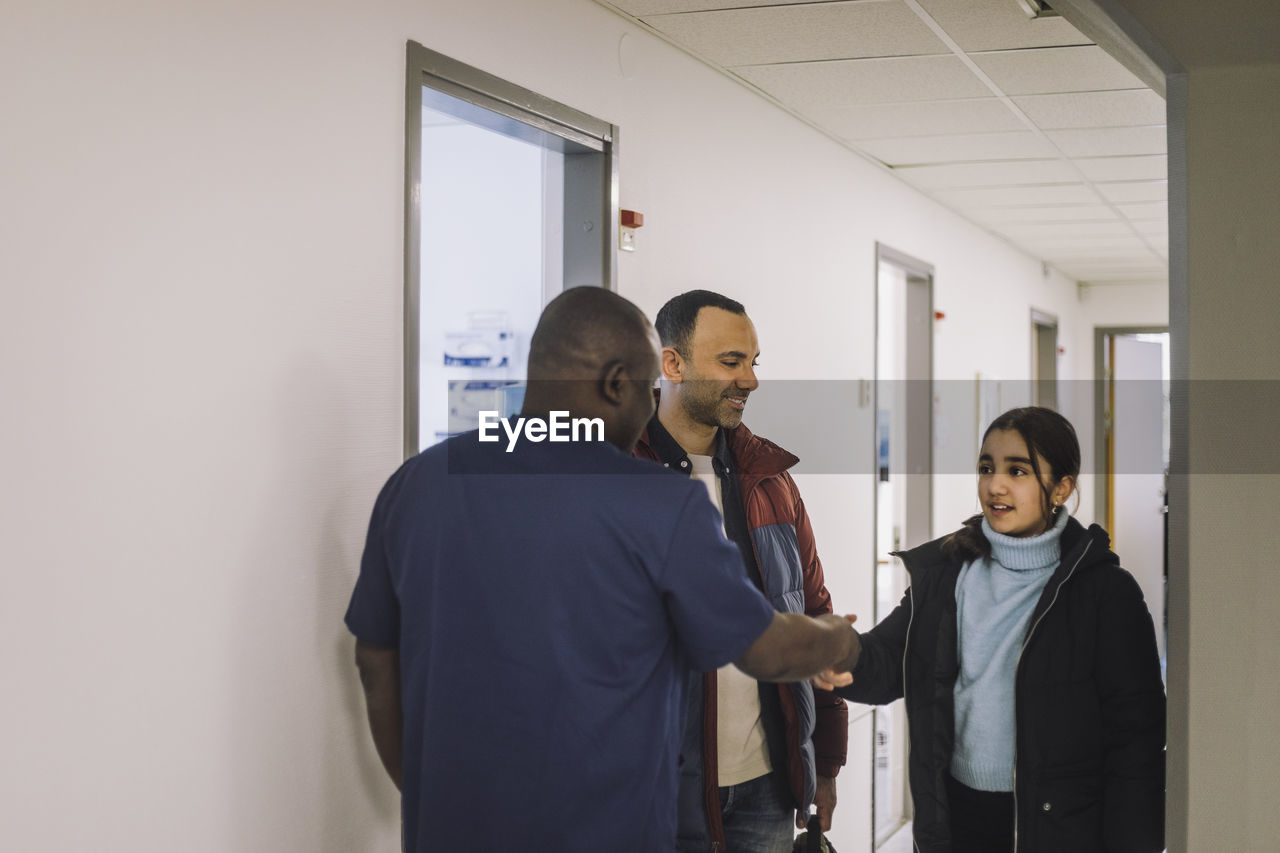 Doctor doing handshake with girl standing at hospital