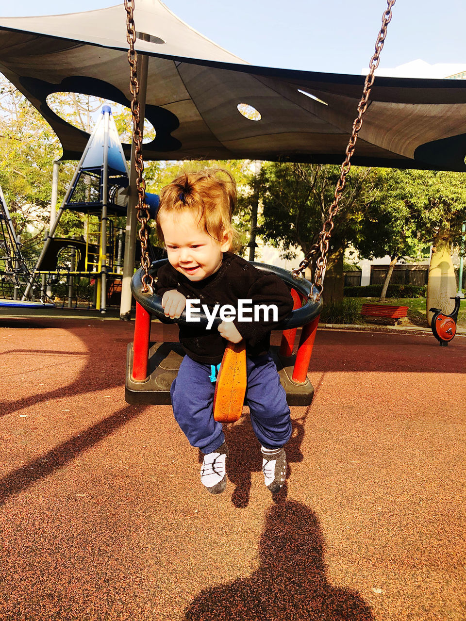 FULL LENGTH OF A BOY PLAYING ON SWING AT PLAYGROUND