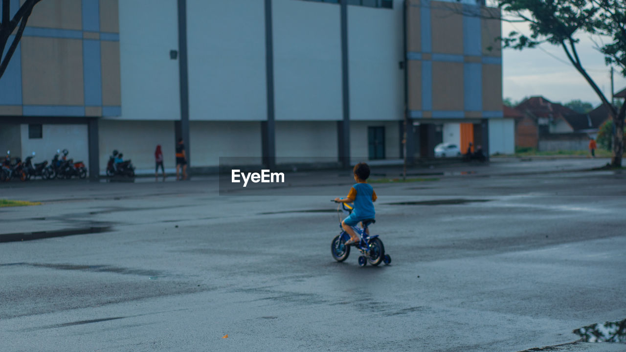 BOY RIDING BICYCLE ON STREET IN CITY