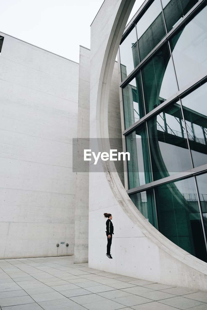 WOMAN WALKING ON MODERN BUILDING