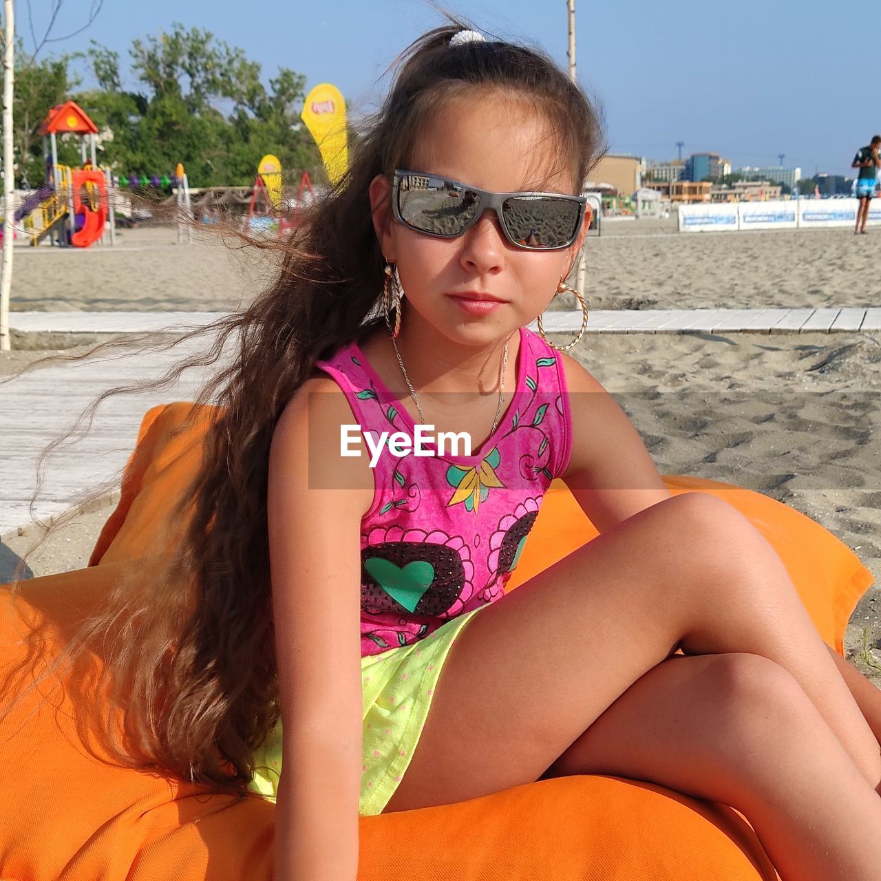 Young woman sitting on sunglasses at beach