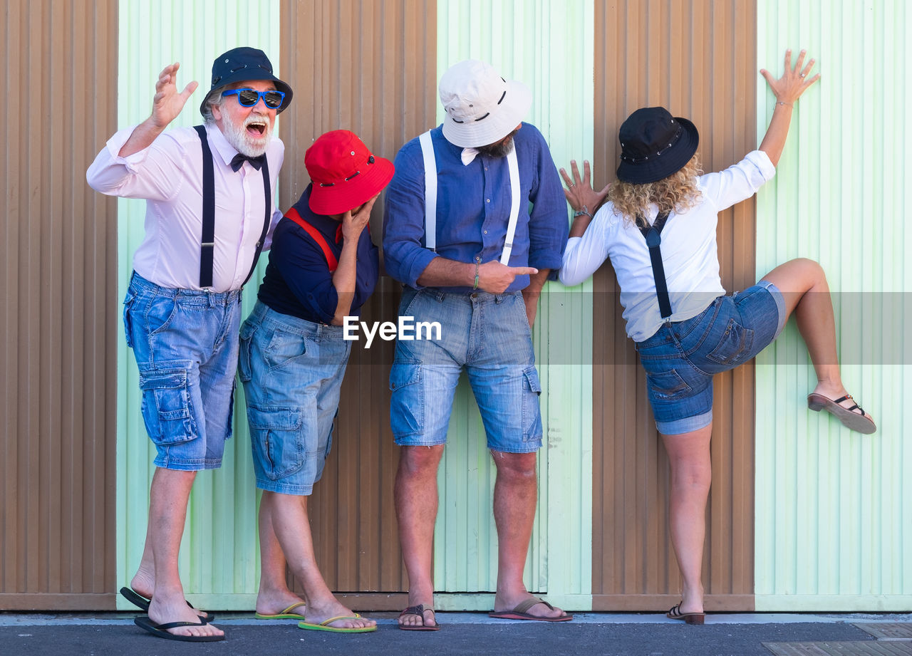 Playful friends standing against wall