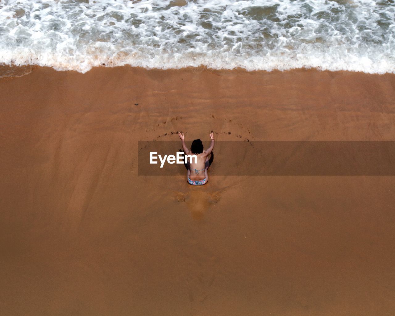 Aerial view of woman sitting on beach