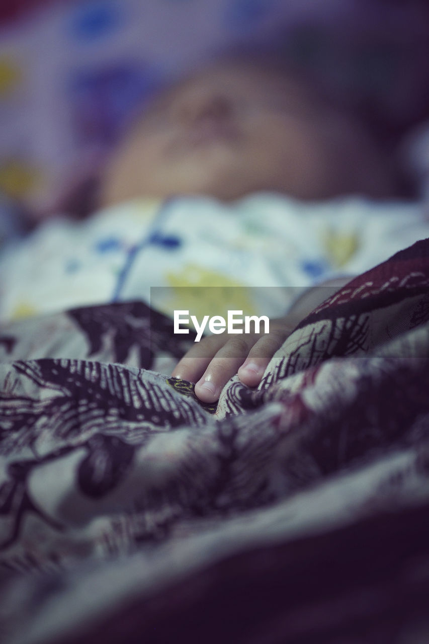 Close-up of baby sleeping on bed at home