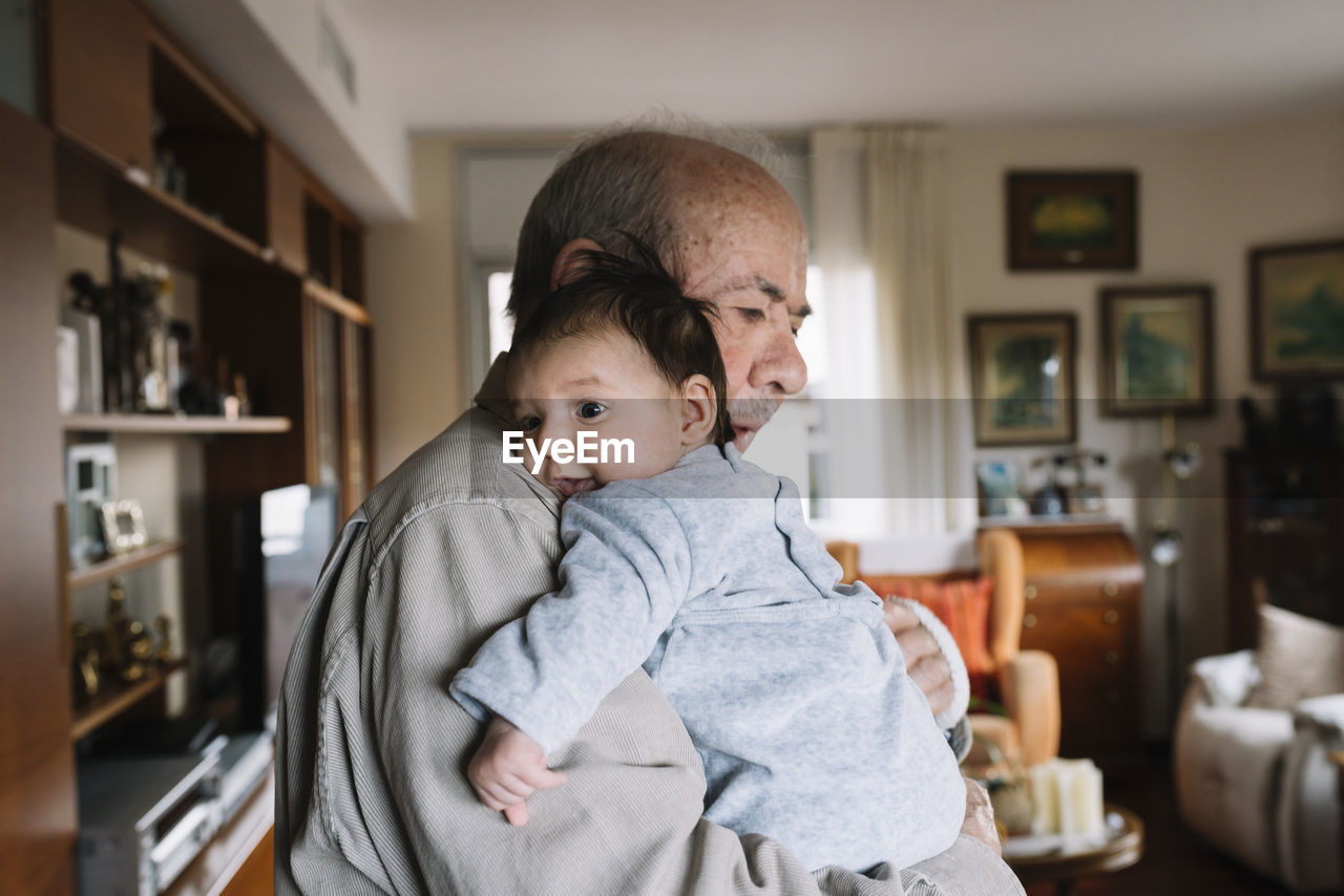 Great-grandfather holding baby at home