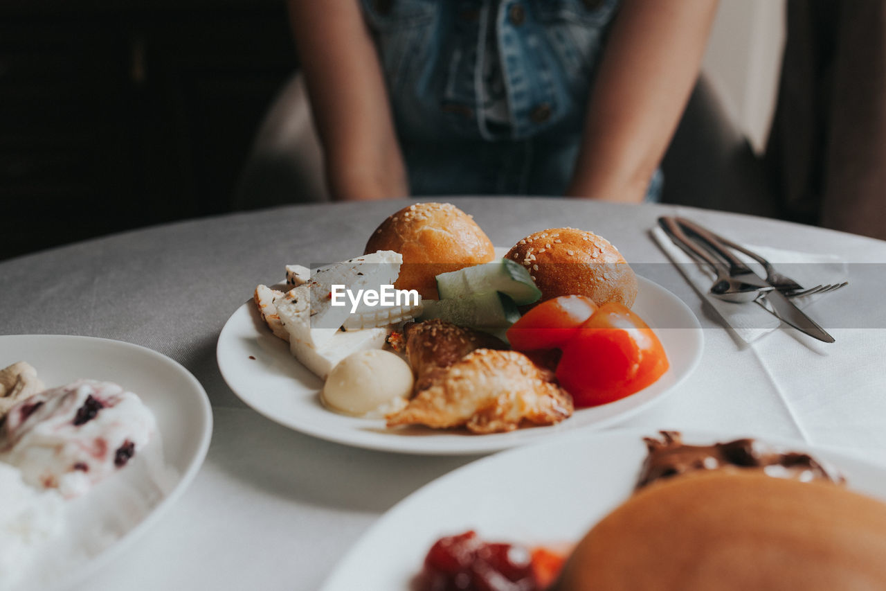Midsection of woman having food in plate at table