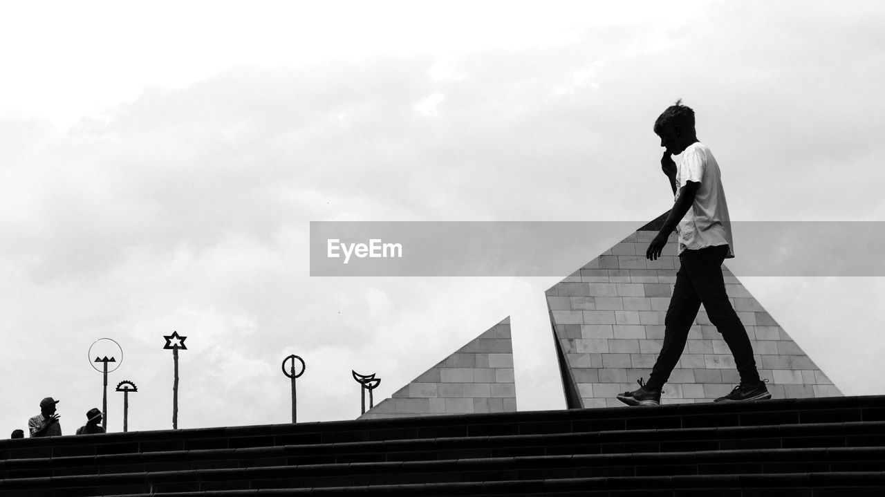 SIDE VIEW OF WOMAN STANDING ON STAIRCASE