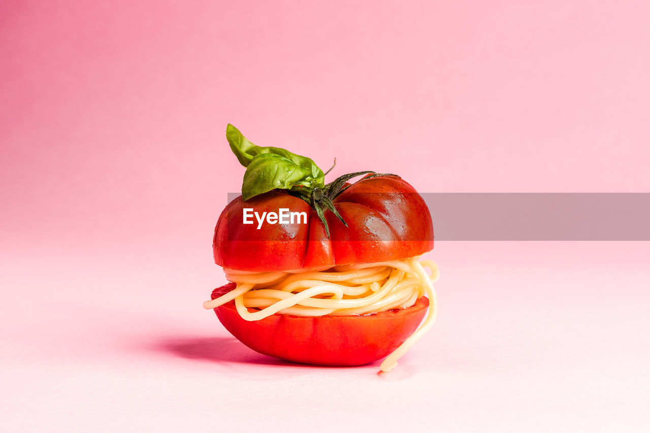 CLOSE-UP OF RED BELL PEPPERS AGAINST PINK BACKGROUND