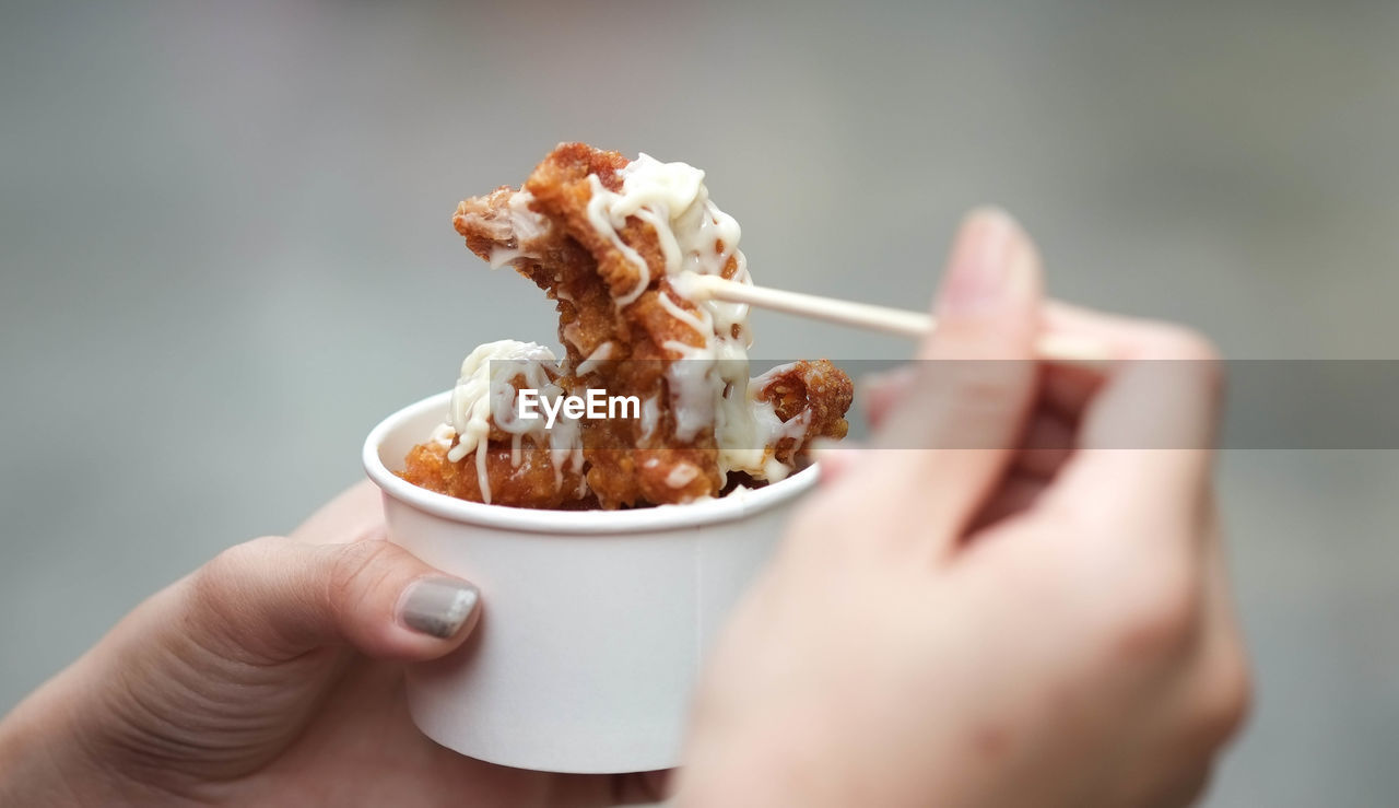 Close-up of woman hand holding fried chicken in cup