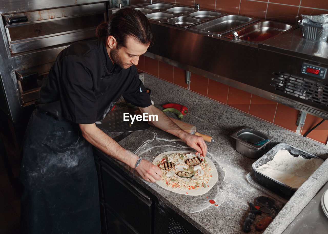 Fresh italian pizza making process. man making pizza at the kitchen