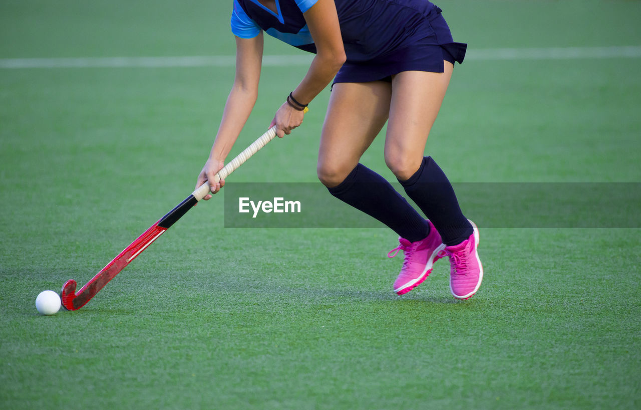 Low section of woman playing hockey in court