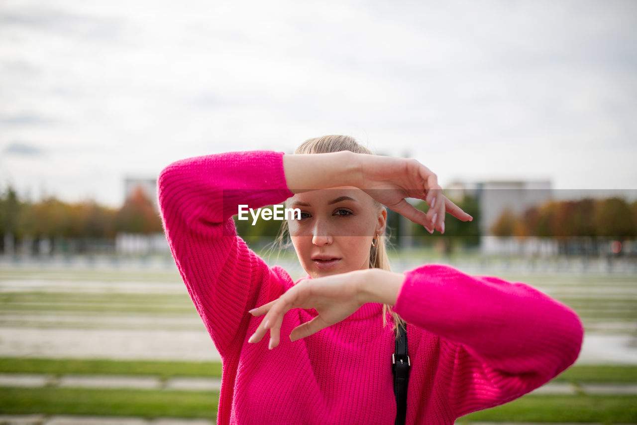 Portrait of young woman gesturing while standing outdoors