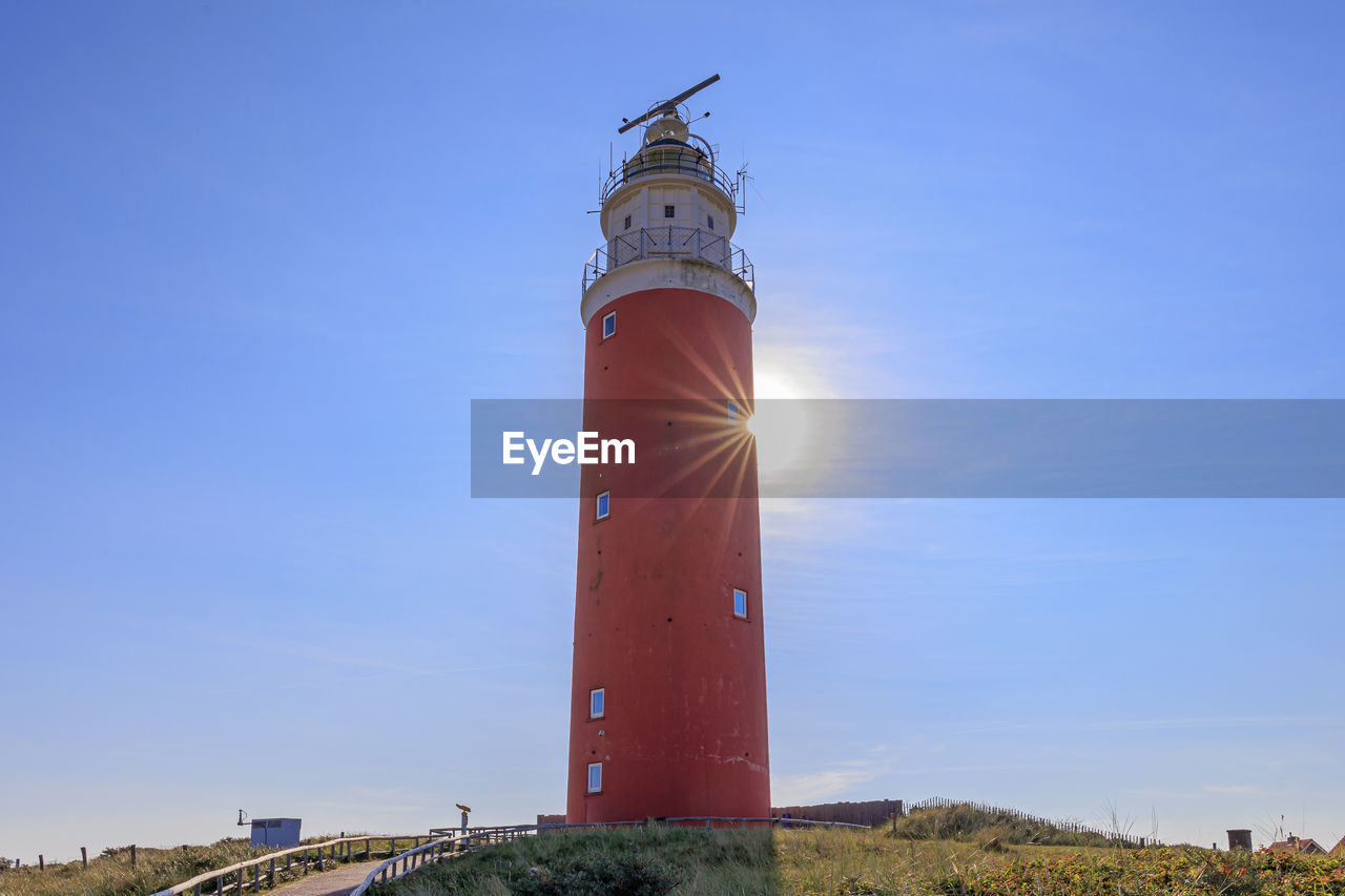 Lighthouse by sea against clear sky