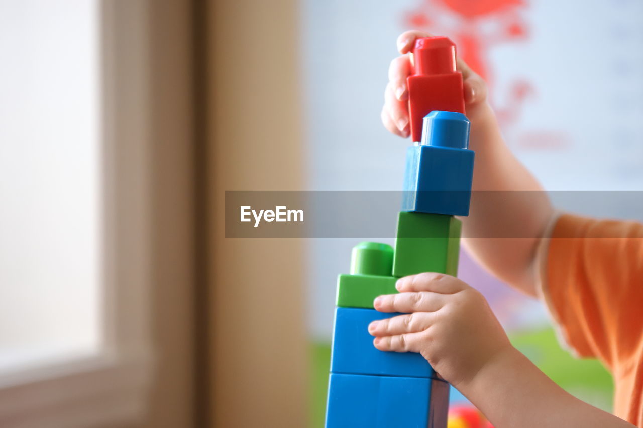 Close-up of child playing with red toy at home