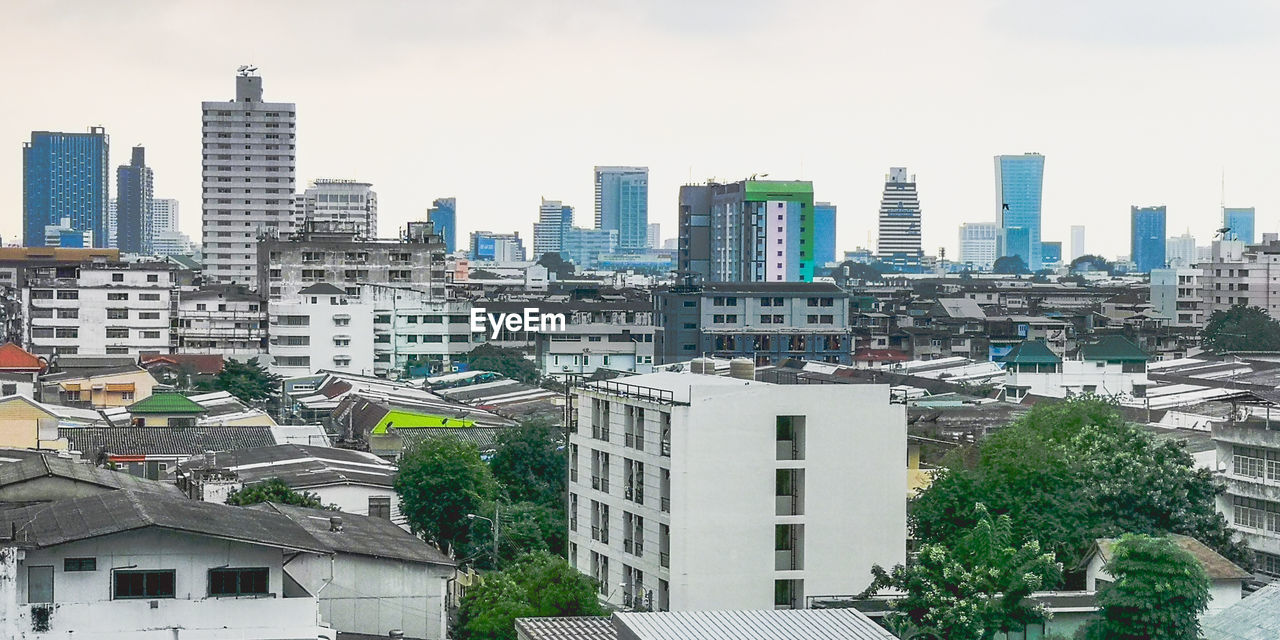 HIGH ANGLE VIEW OF BUILDINGS AND TREES AGAINST SKY