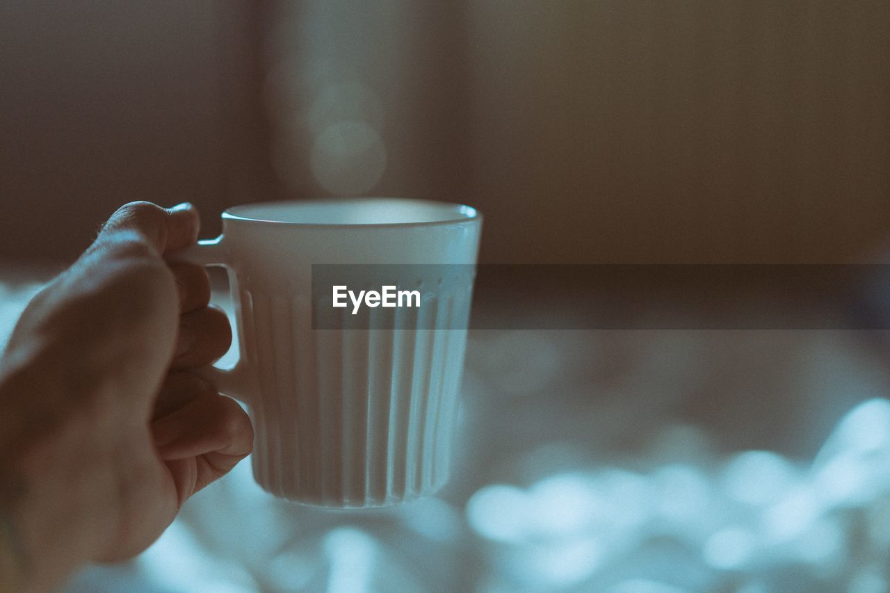 Close-up of human hand holding coffee cup at home