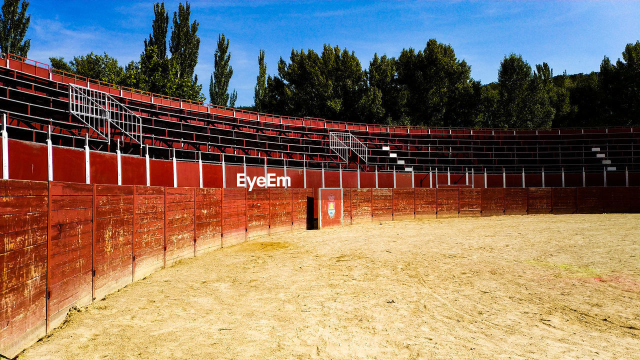 Empty benches on field against sky