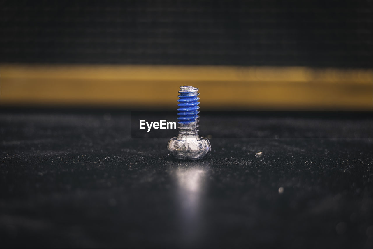 Close-up of screw on black table