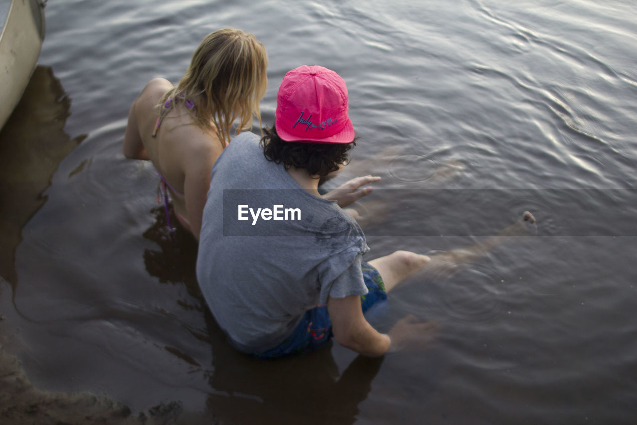 REAR VIEW OF MOTHER AND SON IN LAKE