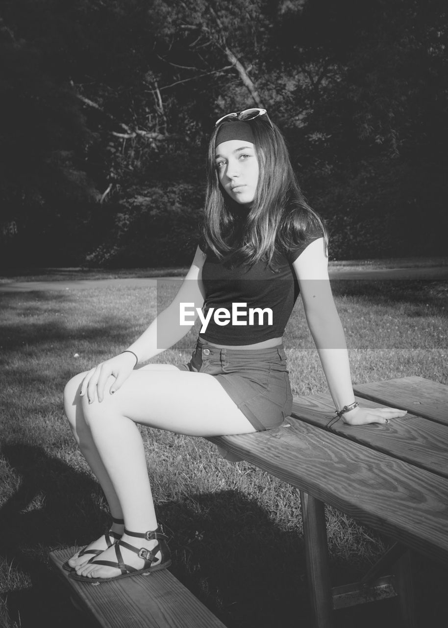 Portrait of teenage girl sitting on table in park