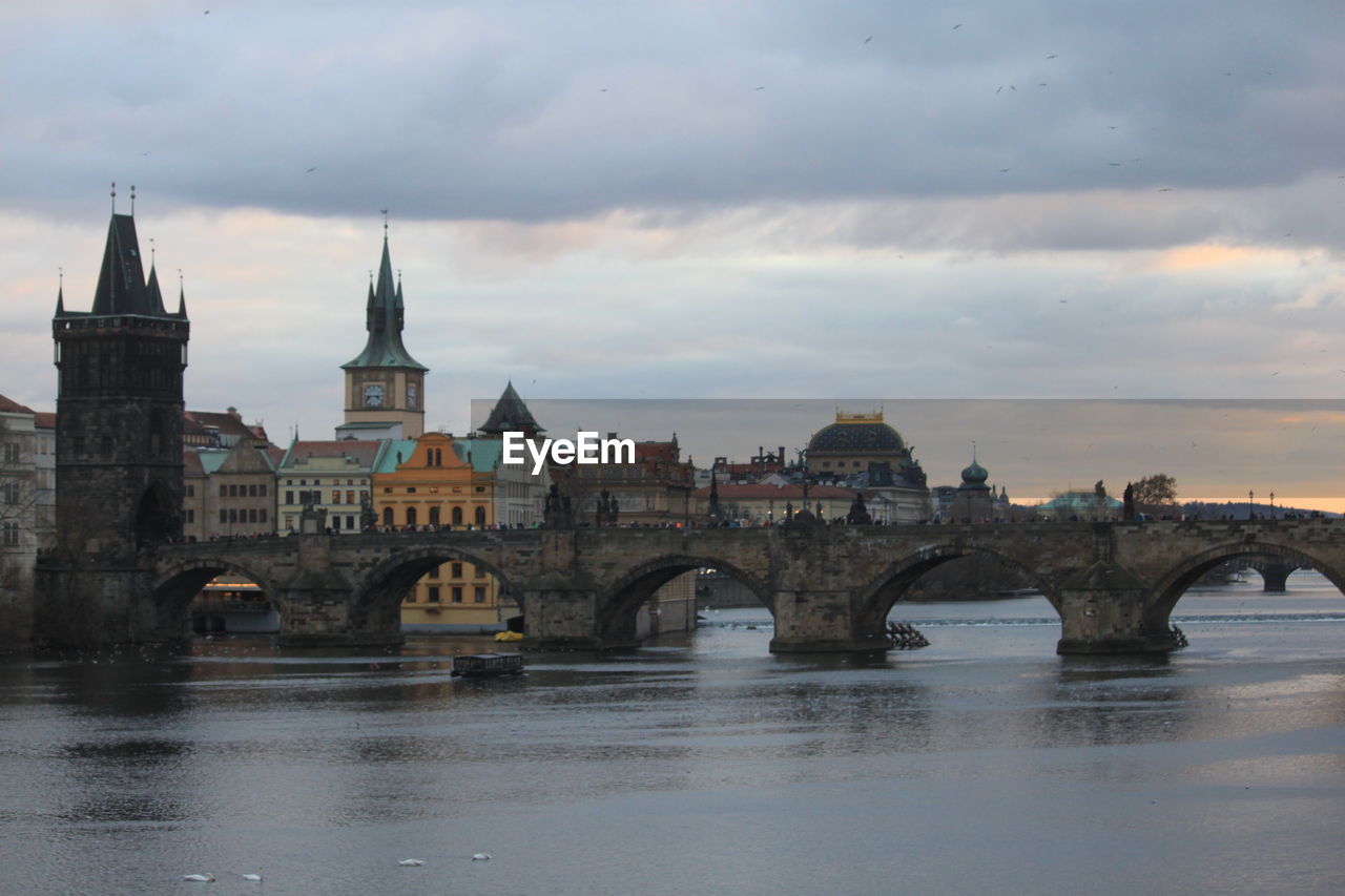 Arch bridge over river against buildings in city