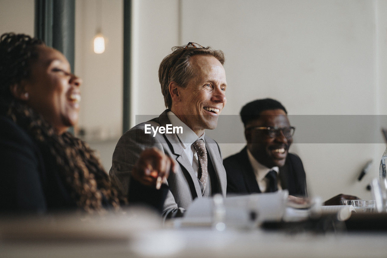 Smiling businessman discussing with colleagues during meeting at office