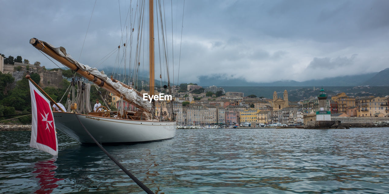 SAILBOAT MOORED IN SEA AGAINST SKY