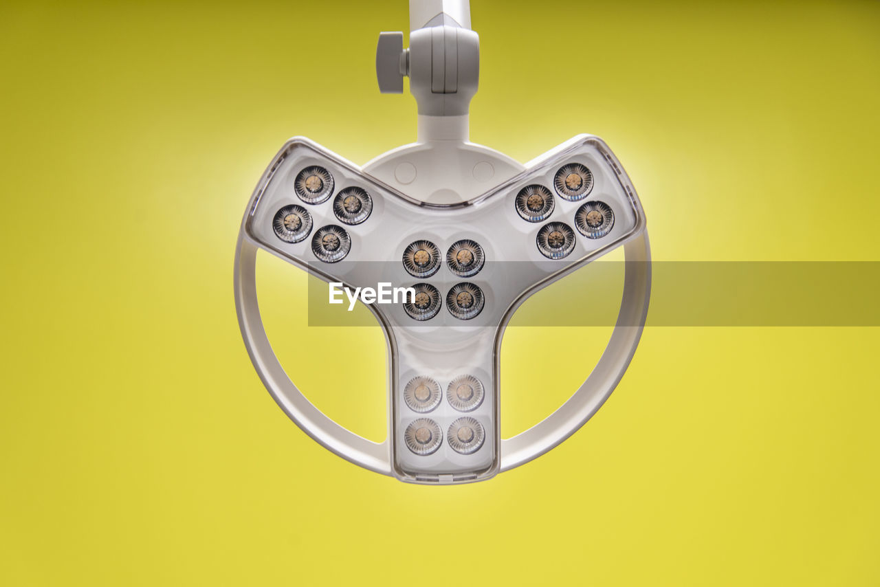 Close-up of lighting equipment against yellow background